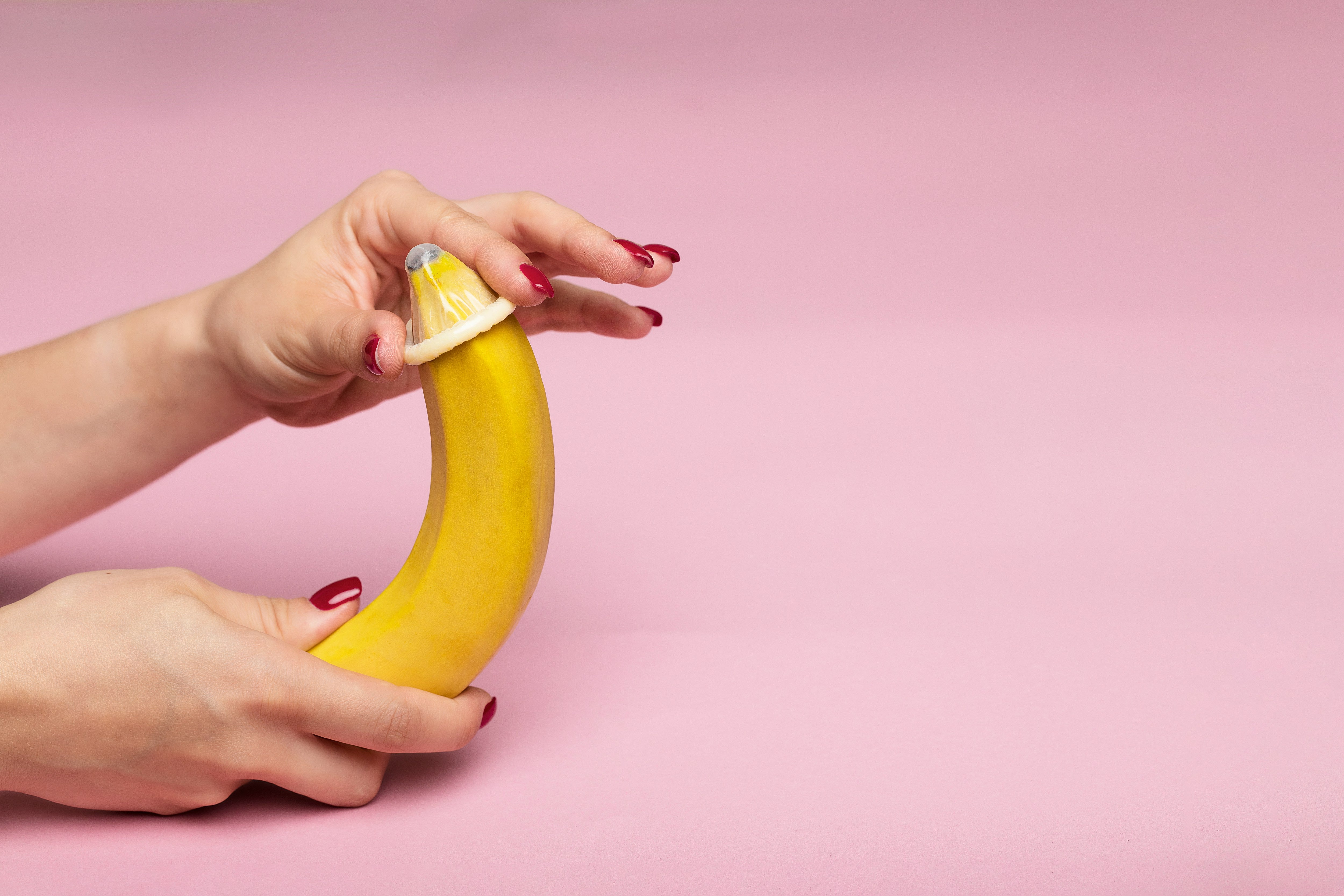 A woman putting a condom on a banana